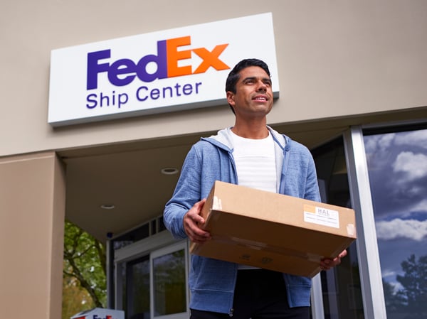 Customer walking out of a FedEx Ship Center with a package